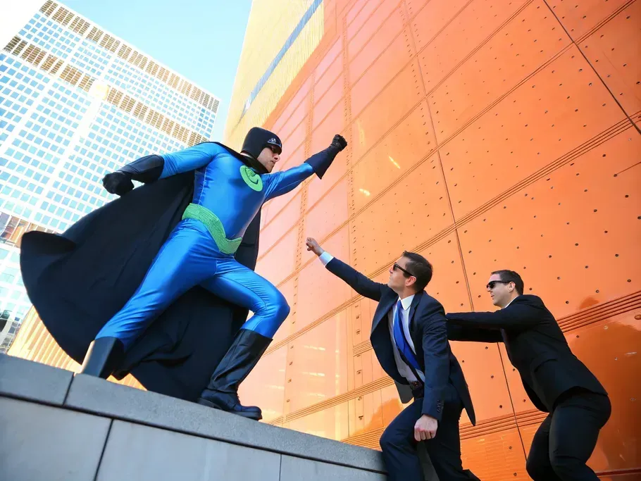 Superhero in blue costume defending against corporate adversaries in an urban setting