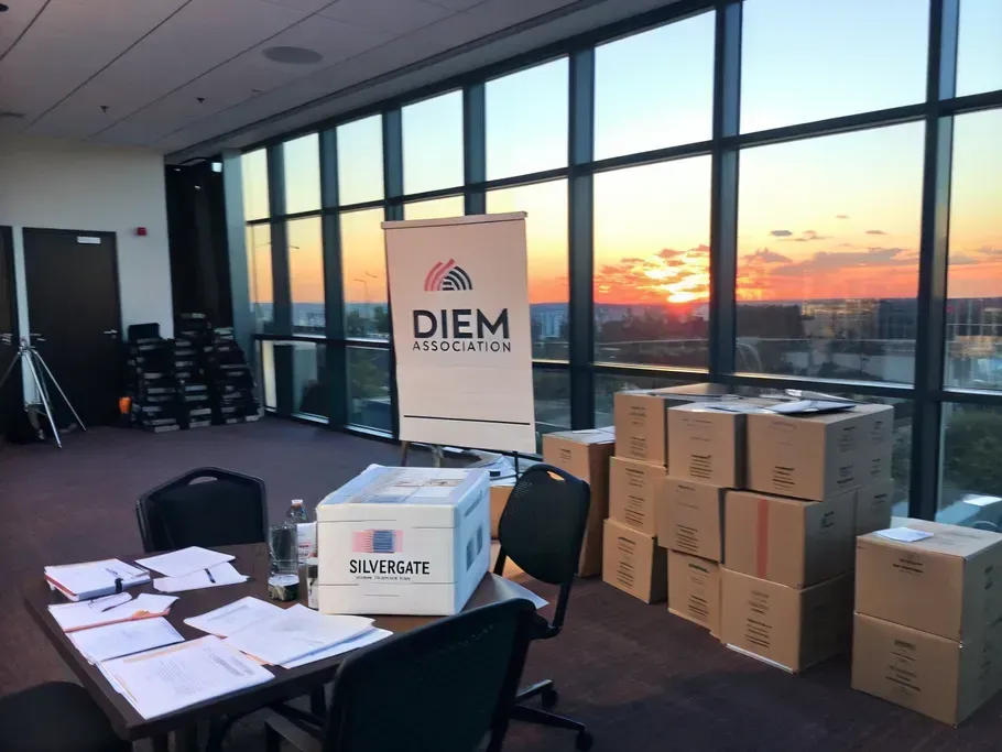 A modern office space being packed up, with boxes labeled 'Diem Association' and a sunset view.