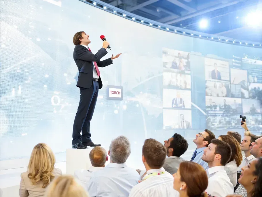 A confident business leader addressing a captivated audience, symbolizing leadership transformation and corporate leadership coaching.