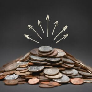 A mound of assorted coins with drawn white arrows pointing upwards, representing the concept of budget allocation in advertising.