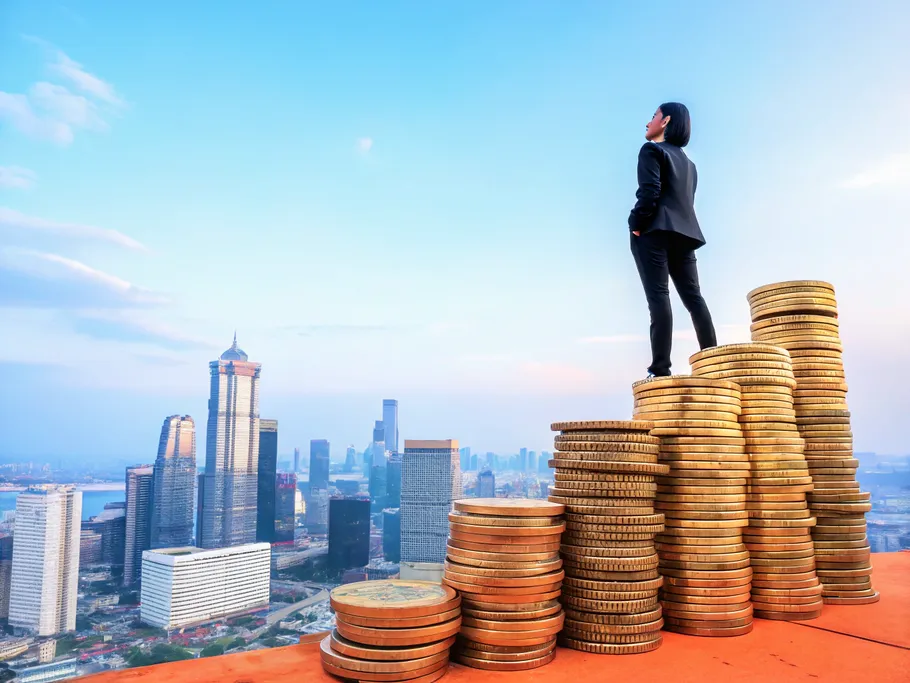 Entrepreneur standing on stacked coins overlooking a city skyline, symbolizing growth in business valuation