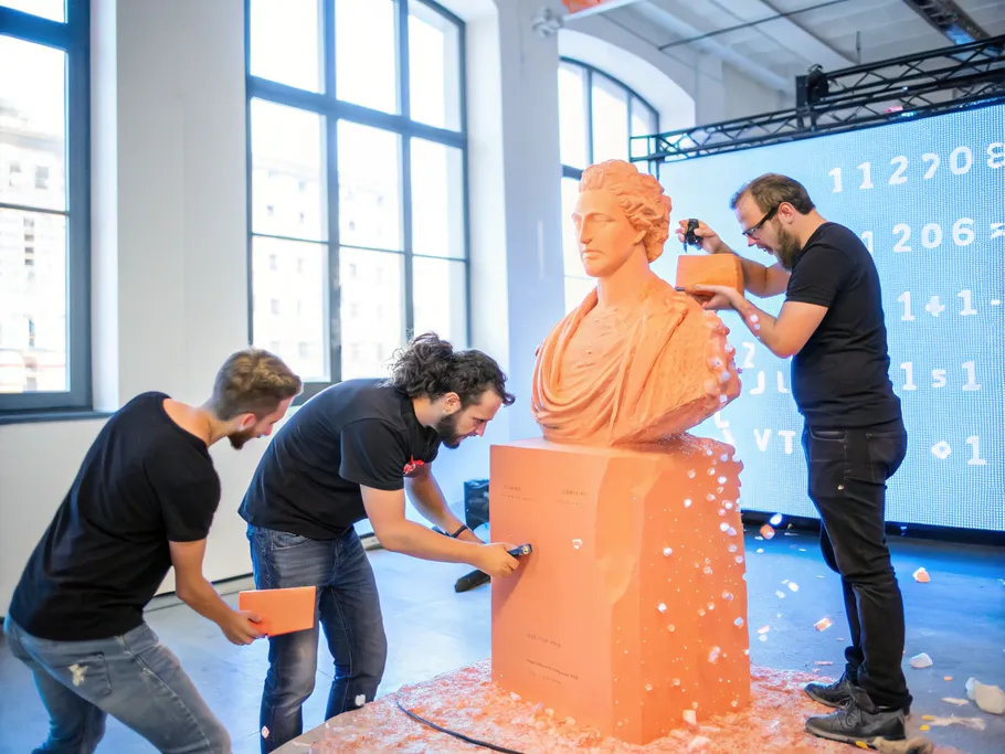 Three founders sculpting a statue from a block of data, surrounded by flying code fragments.