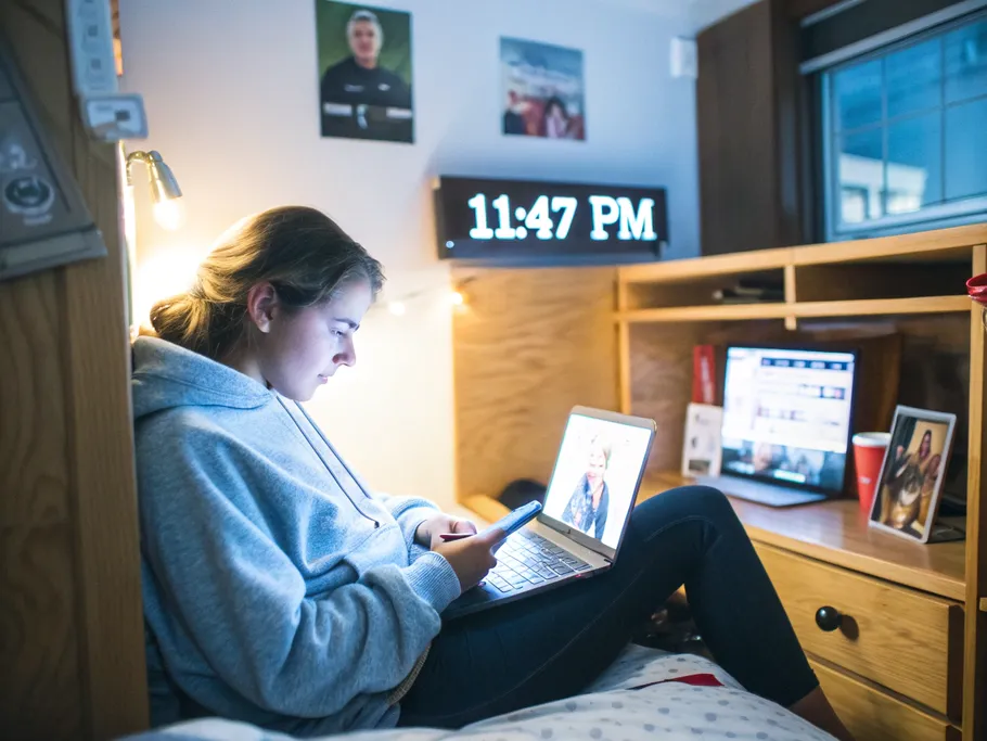 A college student engaging with a digital wellness application in a cozy dorm room late at night.
