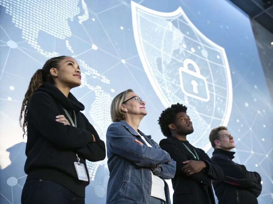 A diverse group of professionals standing confidently in front of a digital shield symbolizing cybersecurity.