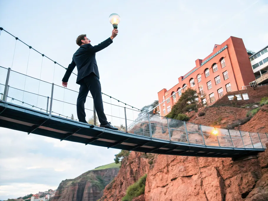 A business professional standing confidently on a transparent energy bridge, connecting two distinct landmasses.