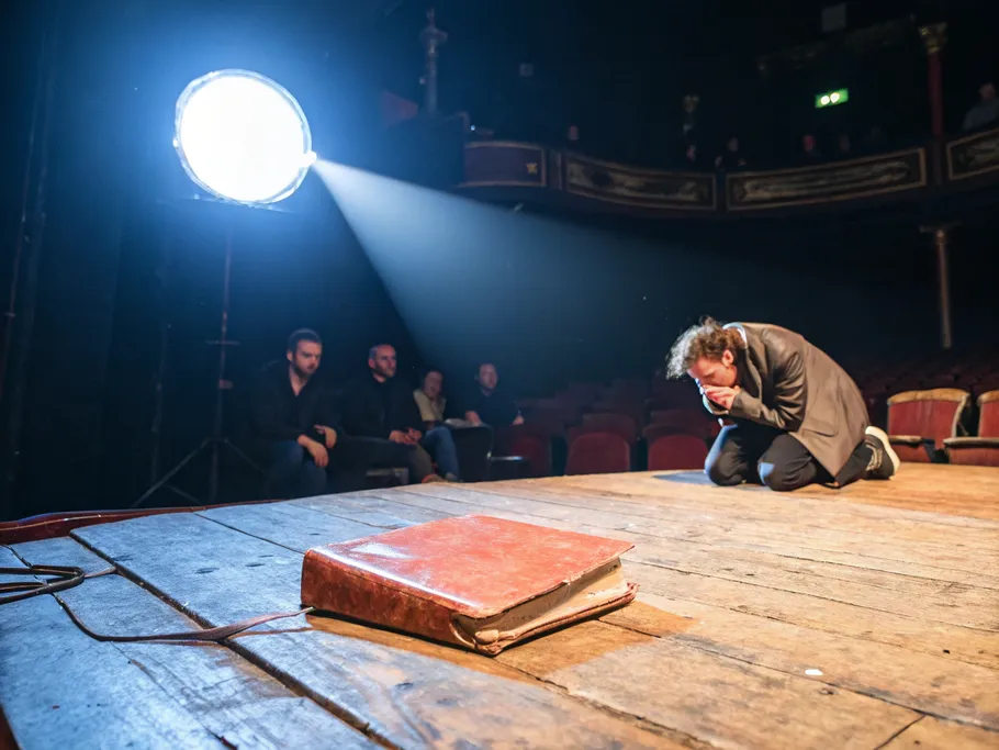 A worn leather manuscript illuminated by a spotlight on a vintage wooden stage, symbolizing the high stakes of storytelling in the publishing industry.